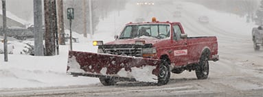 snow plow driving on snow covered street